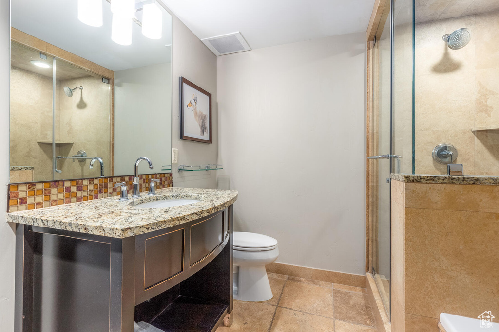 Bathroom featuring walk in shower, backsplash, toilet, tile flooring, and vanity