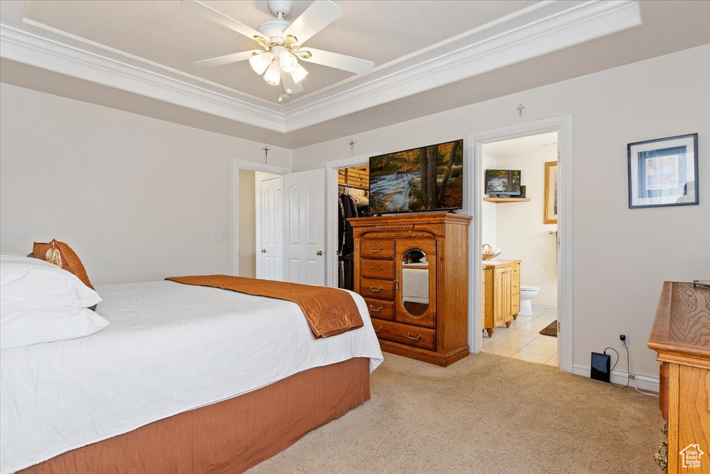 Bedroom featuring light colored carpet, a closet, a tray ceiling, and ceiling fan