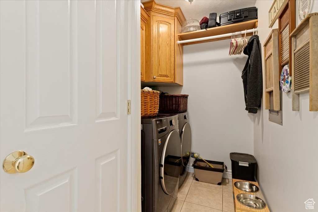 Washroom with cabinets, separate washer and dryer, and light tile floors