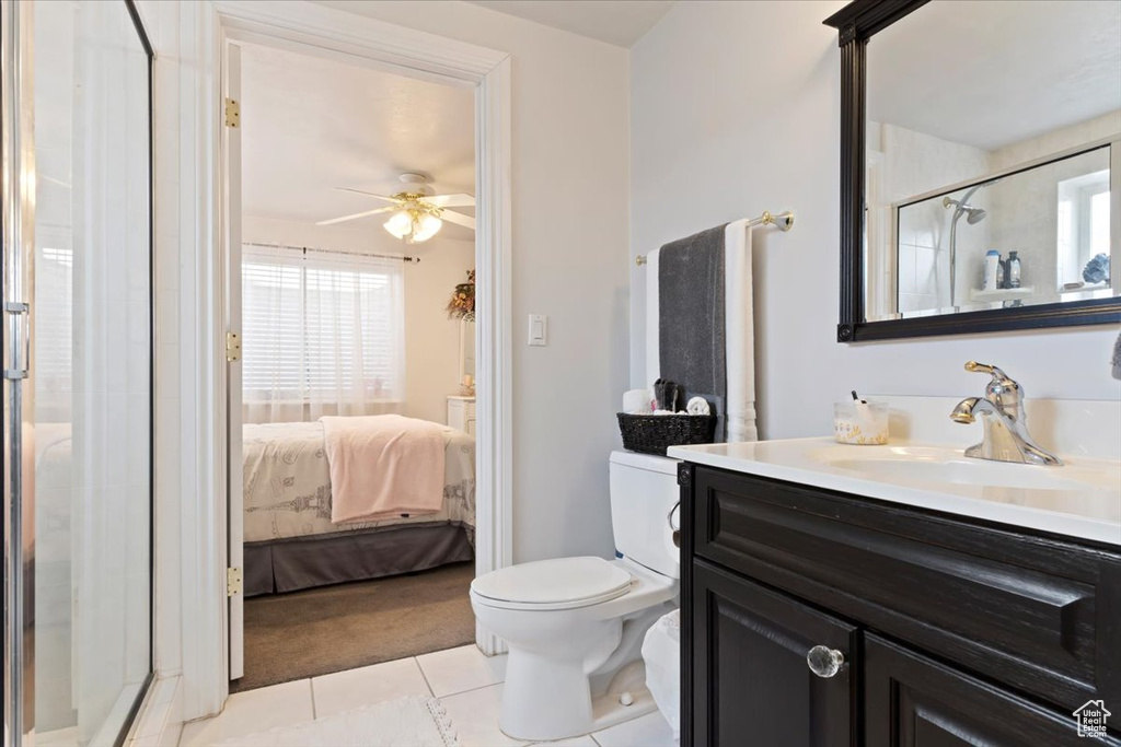 Bathroom featuring ceiling fan, tile floors, walk in shower, toilet, and vanity