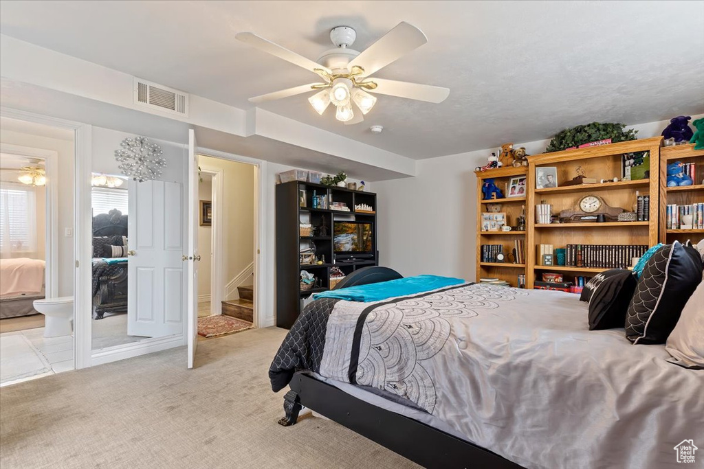 Bedroom featuring light colored carpet, ensuite bathroom, and ceiling fan