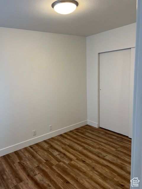 Unfurnished bedroom featuring a closet and dark wood-type flooring