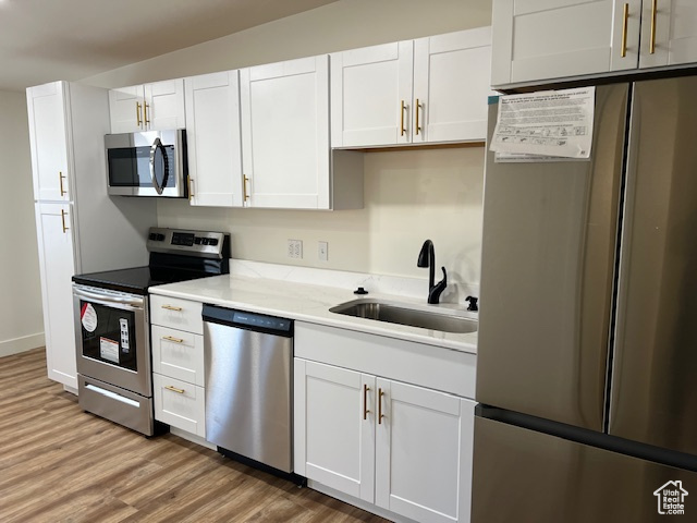 Kitchen featuring white cabinets, appliances with stainless steel finishes, and light hardwood / wood-style floors