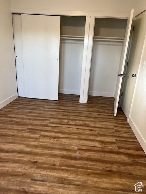 Unfurnished bedroom with multiple closets and dark hardwood / wood-style floors