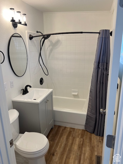 Full bathroom with vanity, toilet, shower / tub combo, and hardwood / wood-style floors