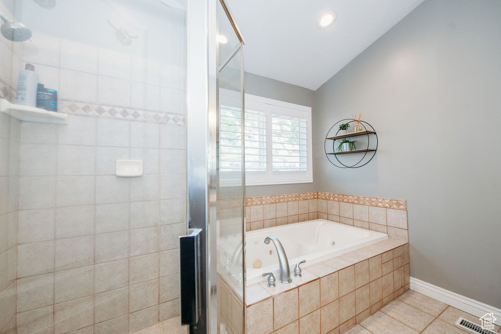 Bathroom featuring tile flooring, vaulted ceiling, and separate shower and tub
