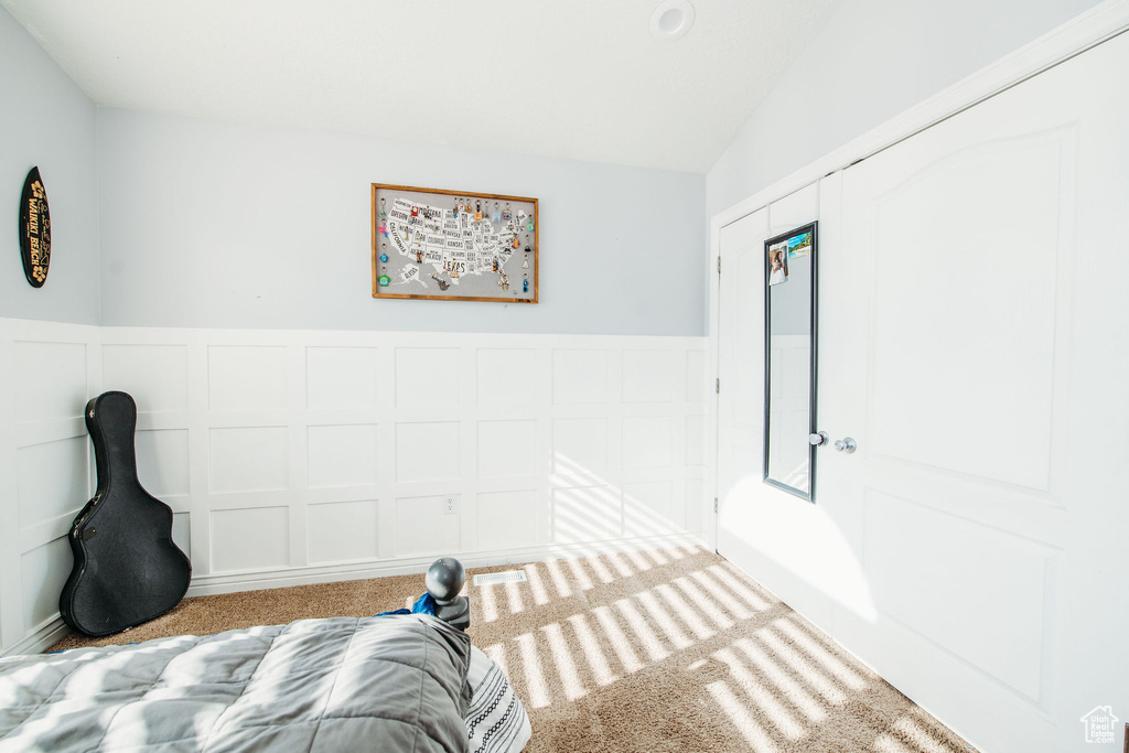 Unfurnished bedroom featuring vaulted ceiling, light colored carpet, and a closet