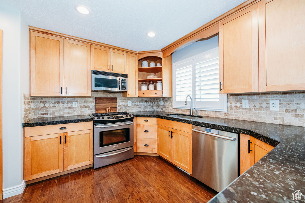 Kitchen with sink, light brown cabinetry, tasteful backsplash, dark hardwood / wood-style flooring, and stainless steel appliances
