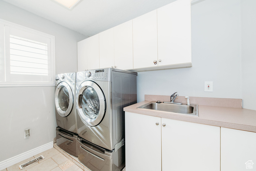 Laundry area with washing machine and dryer, cabinets, light tile floors, and sink