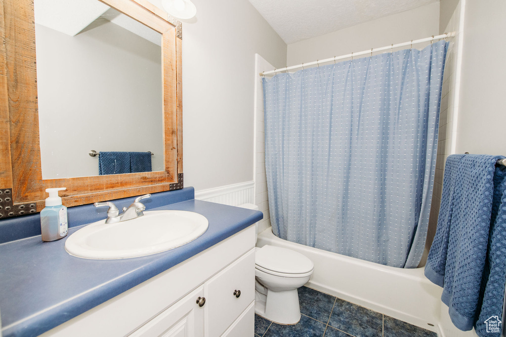 Full bathroom featuring vanity, a textured ceiling, shower / tub combo, toilet, and tile floors