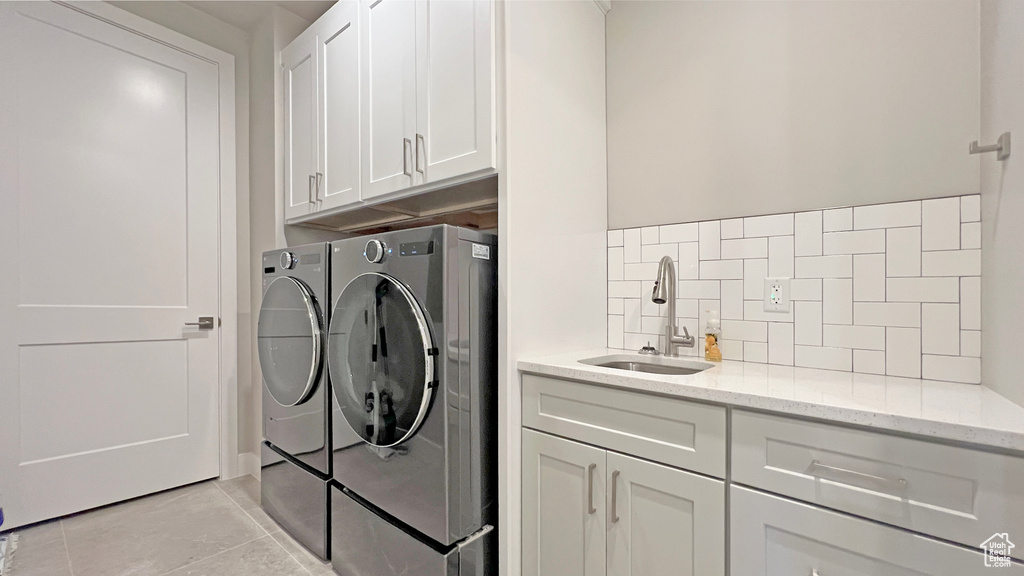 Laundry room featuring sink, cabinets, washing machine and dryer, and light tile floors
