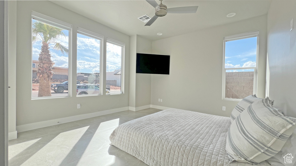 Bedroom featuring light tile flooring, multiple windows, and ceiling fan