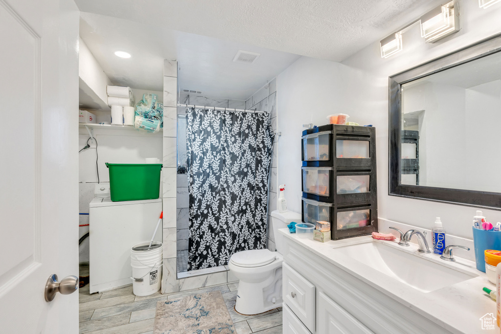 Bathroom with tile flooring, vanity with extensive cabinet space, a textured ceiling, and toilet