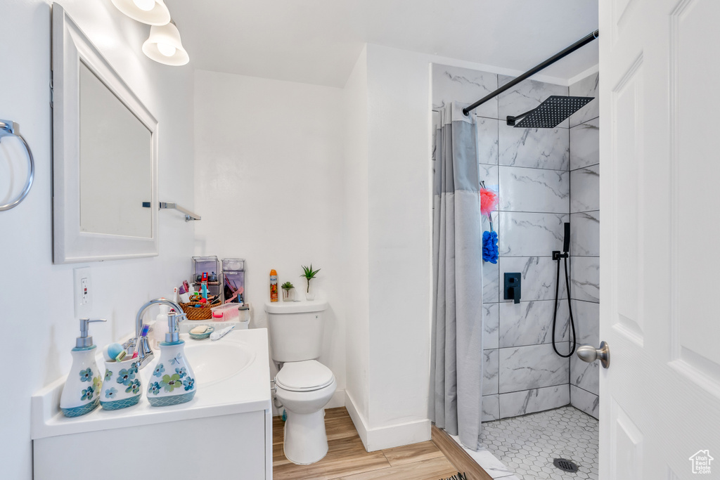 Bathroom with wood-type flooring, large vanity, toilet, and walk in shower
