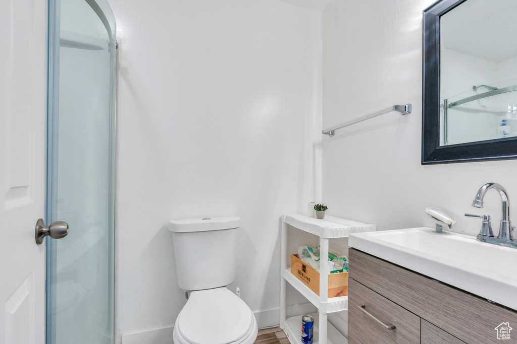Bathroom featuring vanity, toilet, wood-type flooring, and a shower with shower door