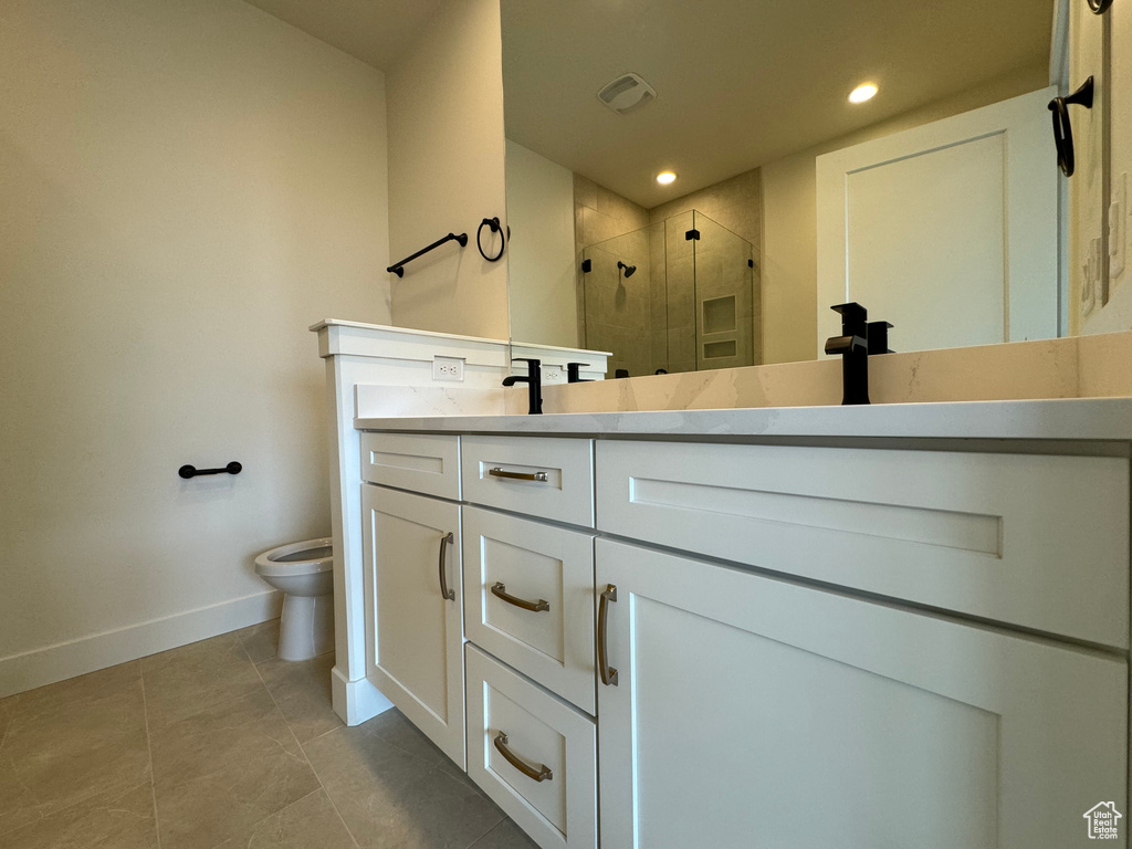 Bathroom featuring tile flooring, toilet, vanity, and walk in shower