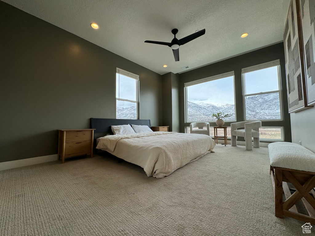 Bedroom with light carpet, a mountain view, a textured ceiling, and ceiling fan