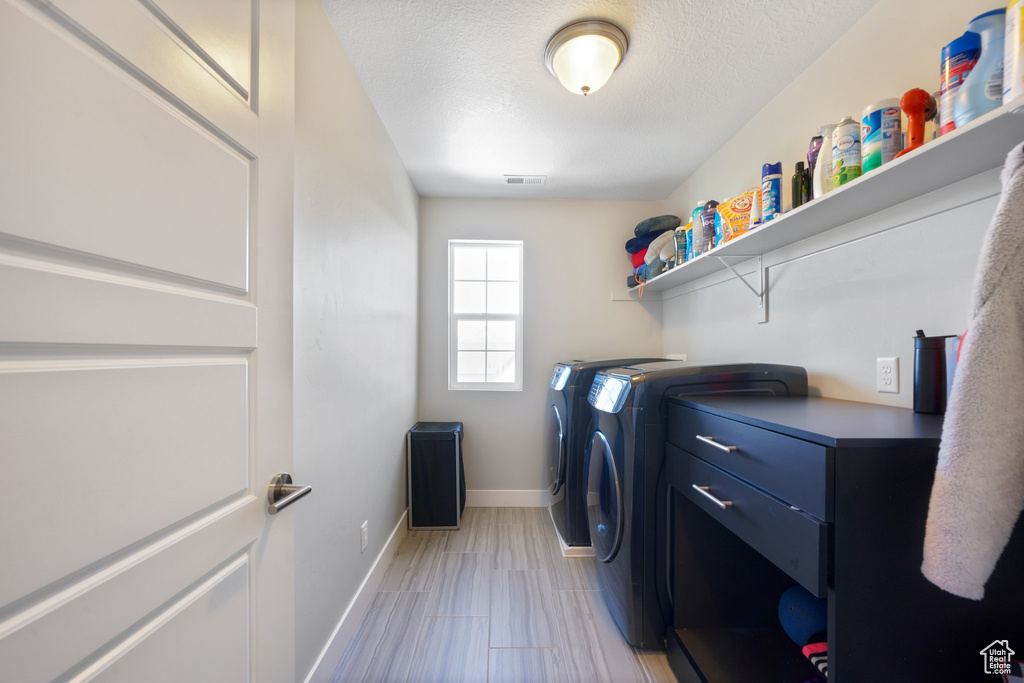 Laundry area featuring washer and clothes dryer, a textured ceiling, and light tile floors