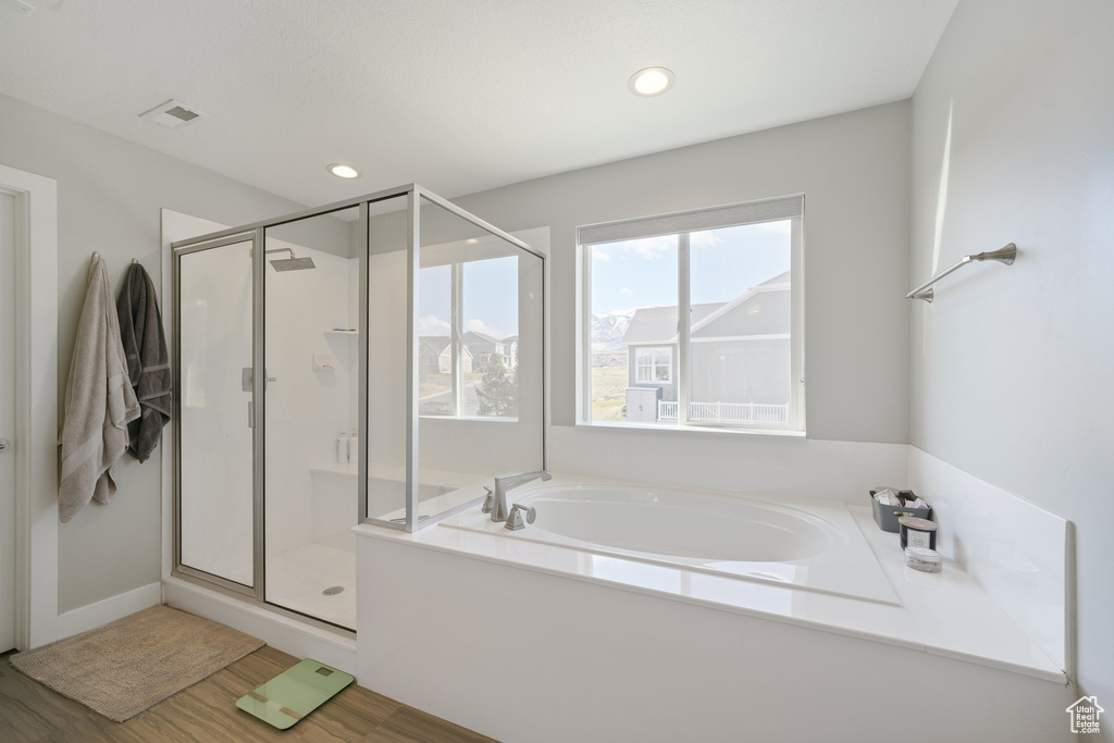 Bathroom with independent shower and bath and hardwood / wood-style floors