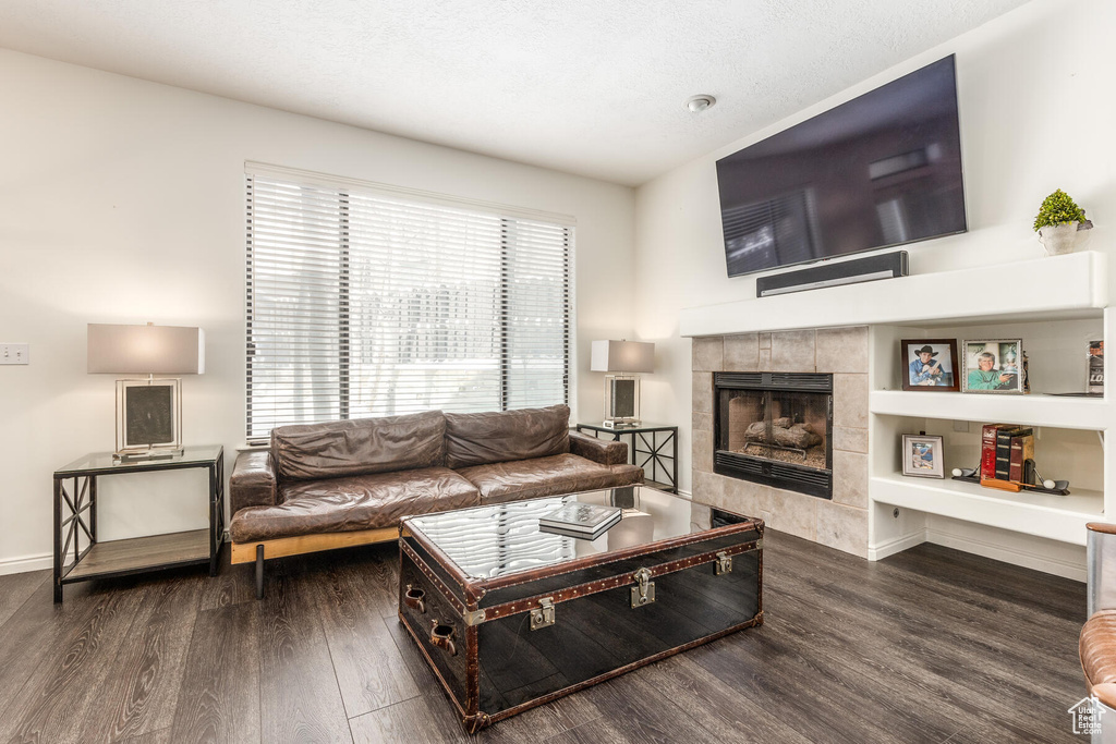 Living room featuring dark hardwood / wood-style floors, a tiled fireplace, and built in shelves
