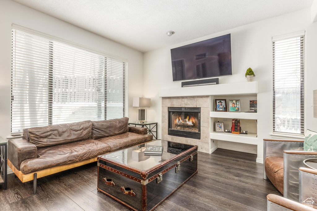 Living room featuring a wealth of natural light, dark hardwood / wood-style flooring, a tile fireplace, and built in features