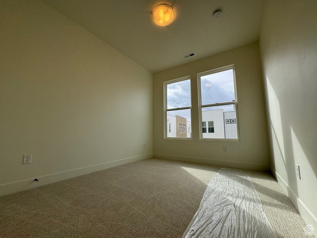 Unfurnished room with light carpet and vaulted ceiling