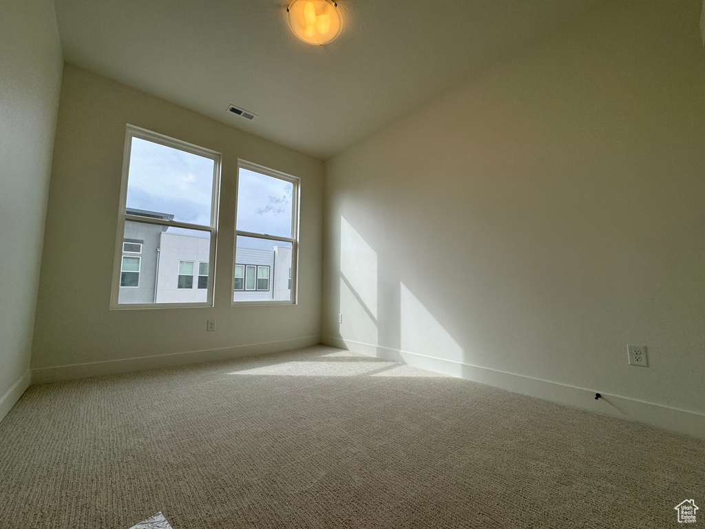 Empty room with vaulted ceiling and light carpet