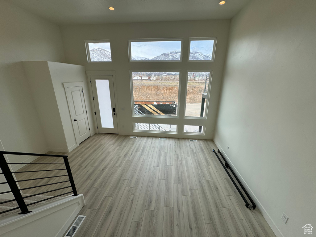 Entryway featuring a baseboard radiator, a high ceiling, and light hardwood / wood-style flooring