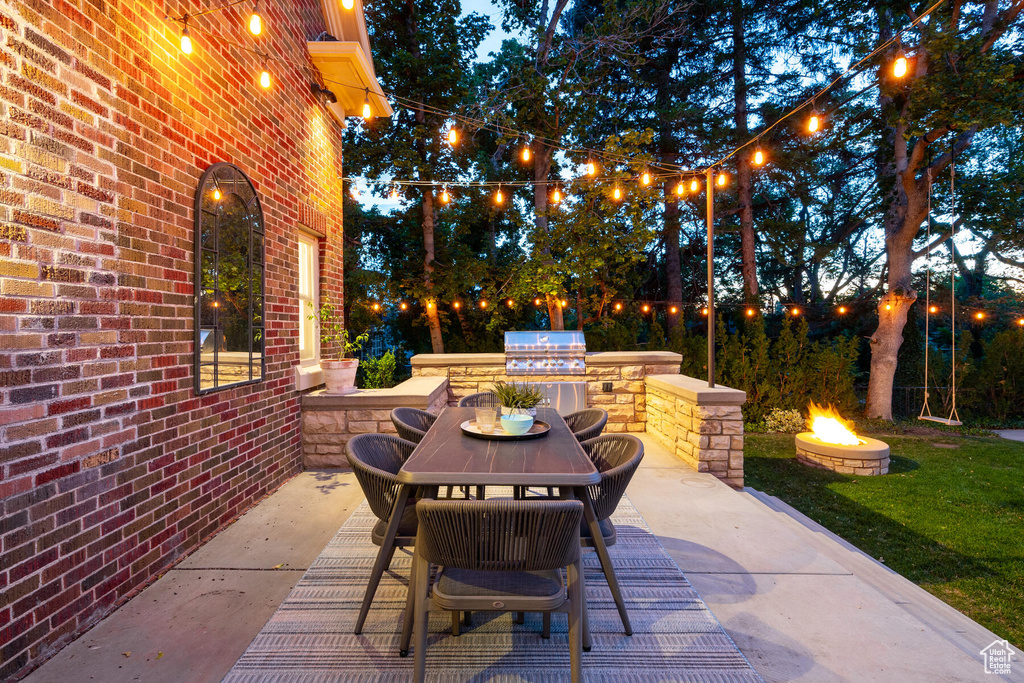 View of patio featuring an outdoor kitchen, a fire pit, and grilling area