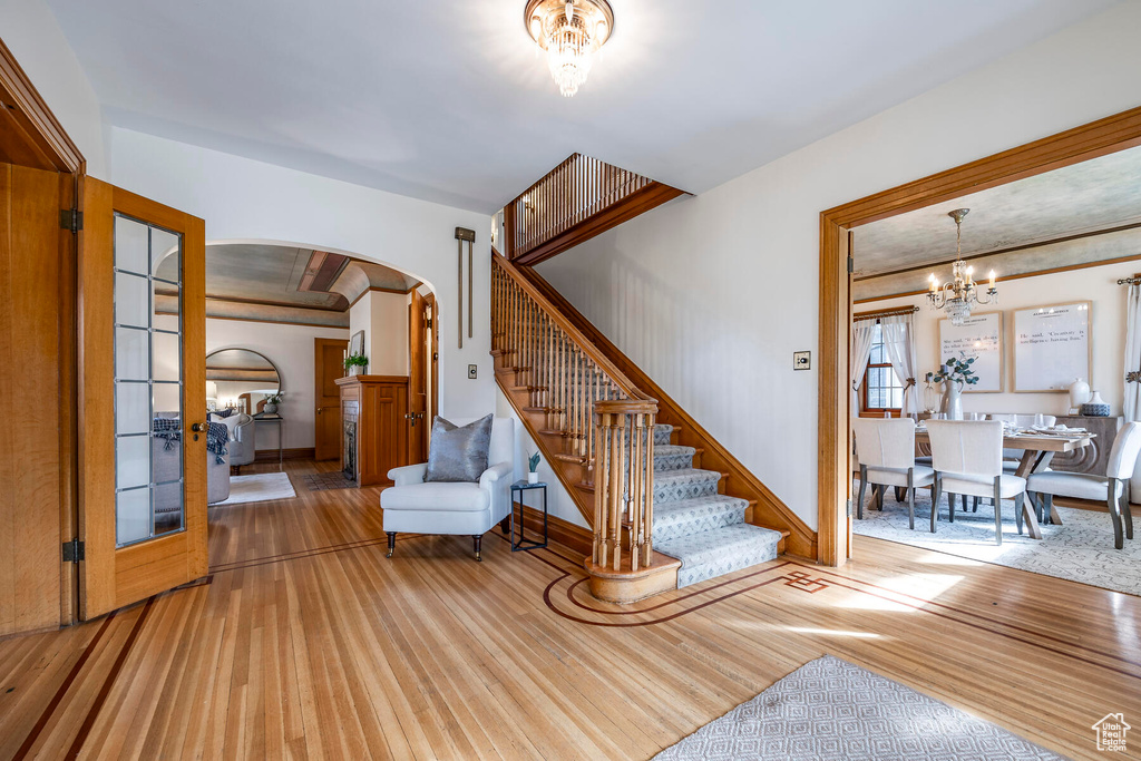Stairway featuring an inviting chandelier, french doors, and light hardwood / wood-style floors