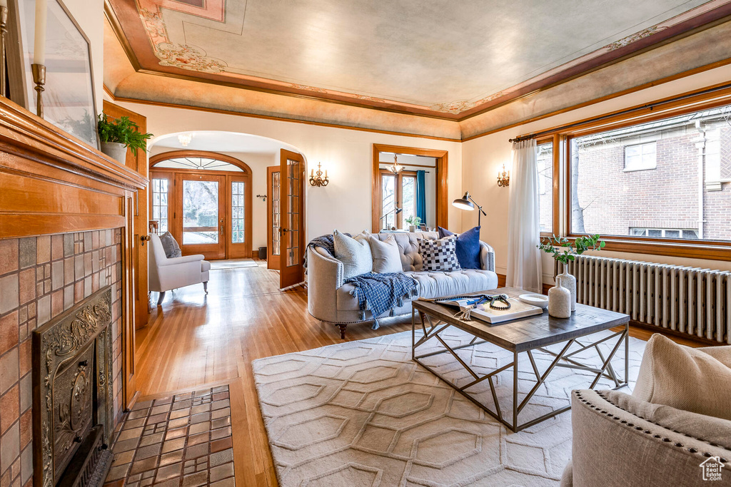 Living room featuring radiator, light hardwood / wood-style flooring, and a raised ceiling