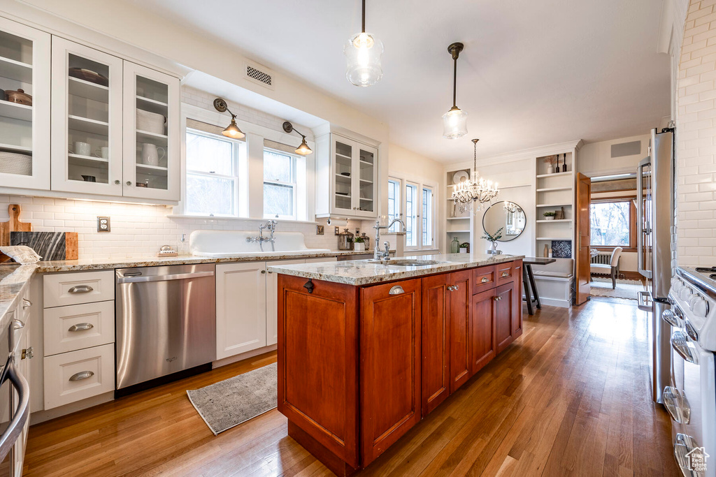 Kitchen with a notable chandelier, white cabinets, a healthy amount of sunlight, and dishwasher
