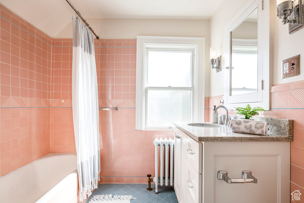 Bathroom with tile flooring, radiator, vanity, and a healthy amount of sunlight