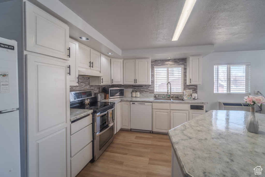 Kitchen featuring white cabinets, stainless steel appliances, sink, and light hardwood / wood-style floors
