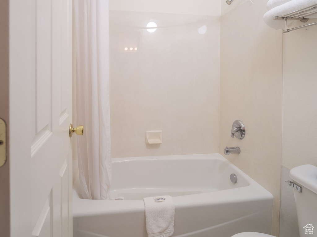 Bathroom with toilet, shower / bathtub combination with curtain, and tile floors