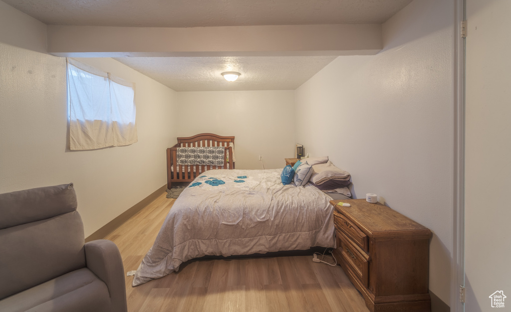 Bedroom featuring light hardwood / wood-style floors and beamed ceiling