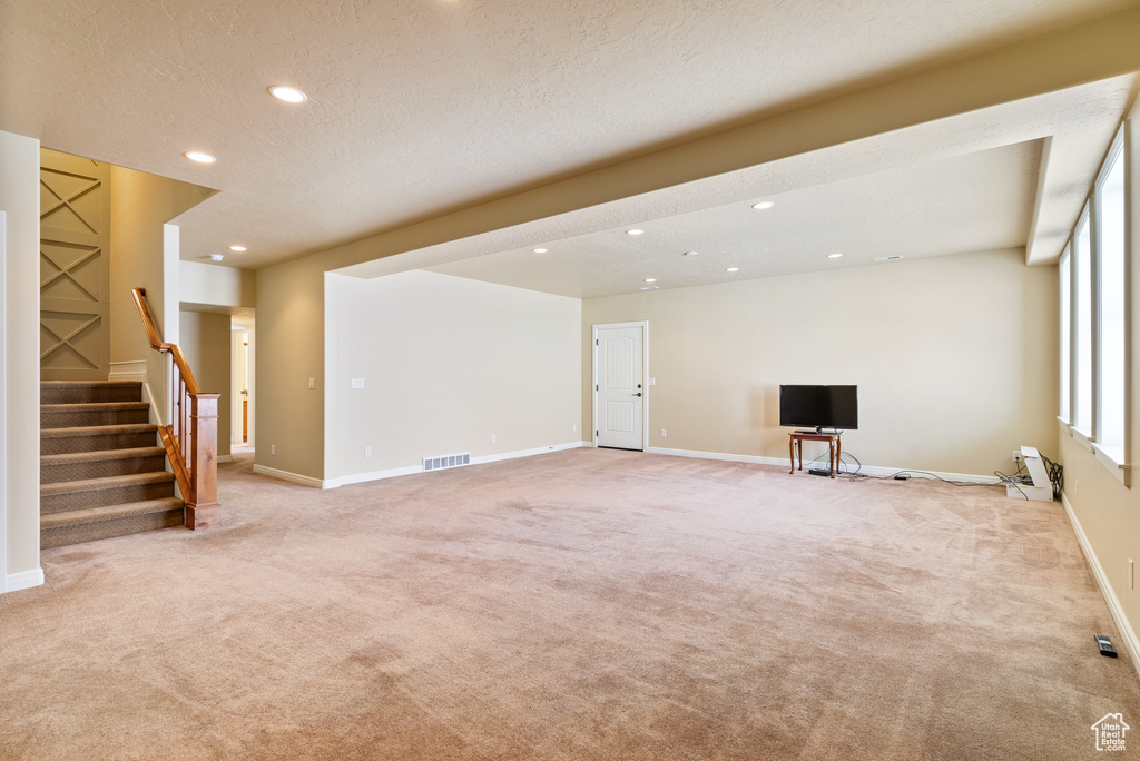 Unfurnished living room with a textured ceiling and light colored carpet