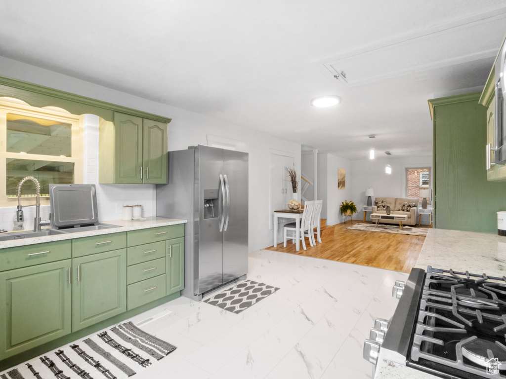 Kitchen with sink, stainless steel fridge, green cabinetry, and light tile flooring