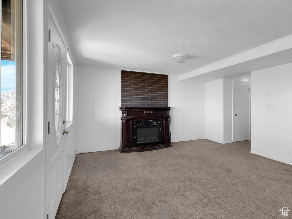 Unfurnished living room featuring a wealth of natural light, carpet floors, brick wall, and a fireplace
