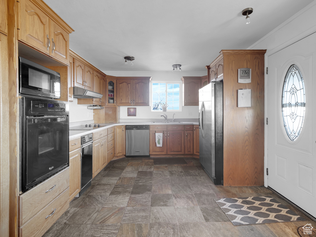 Kitchen featuring black appliances, sink, and crown molding