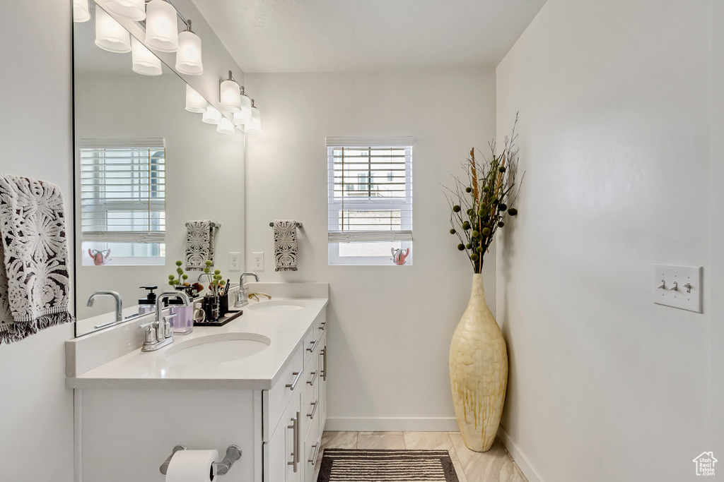 Bathroom featuring a wealth of natural light, tile flooring, and dual bowl vanity