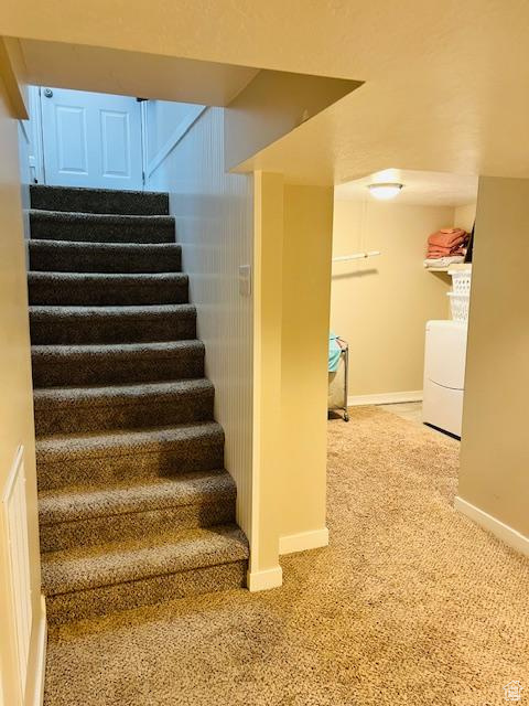 Stairs featuring light colored carpet and independent washer and dryer