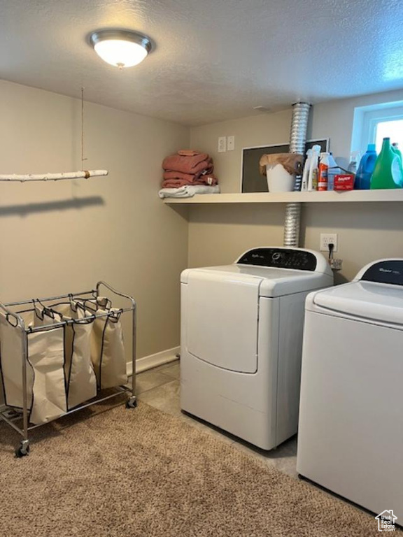 Clothes washing area featuring light colored carpet, a textured ceiling, and washer and dryer