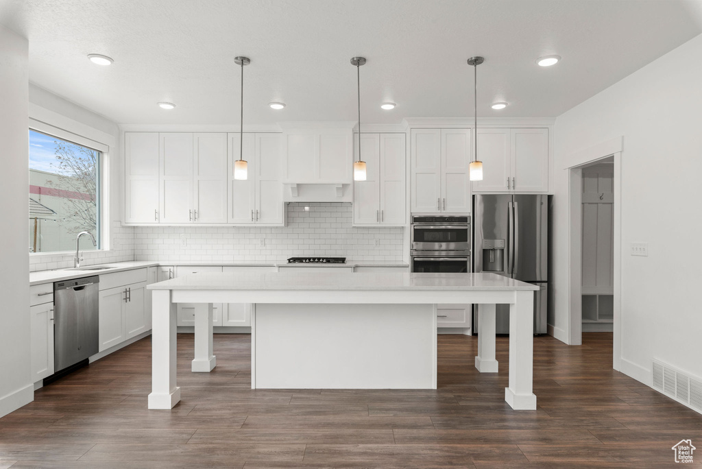 Kitchen featuring appliances with stainless steel finishes, pendant lighting, a breakfast bar, and a kitchen island