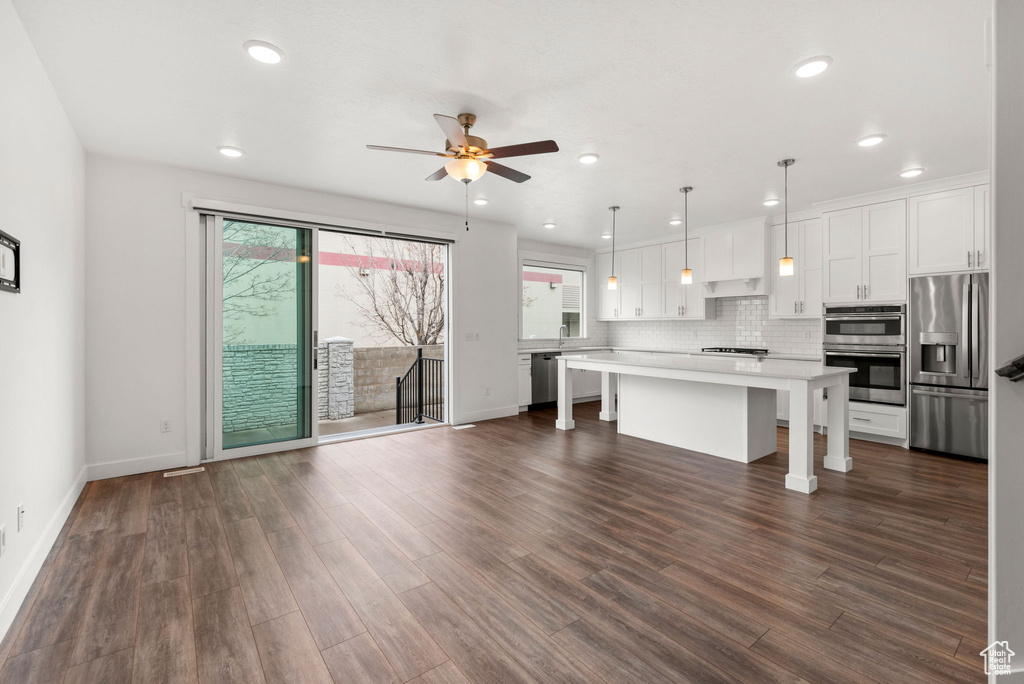 Kitchen featuring ceiling fan, decorative light fixtures, a center island, white cabinetry, and stainless steel appliances