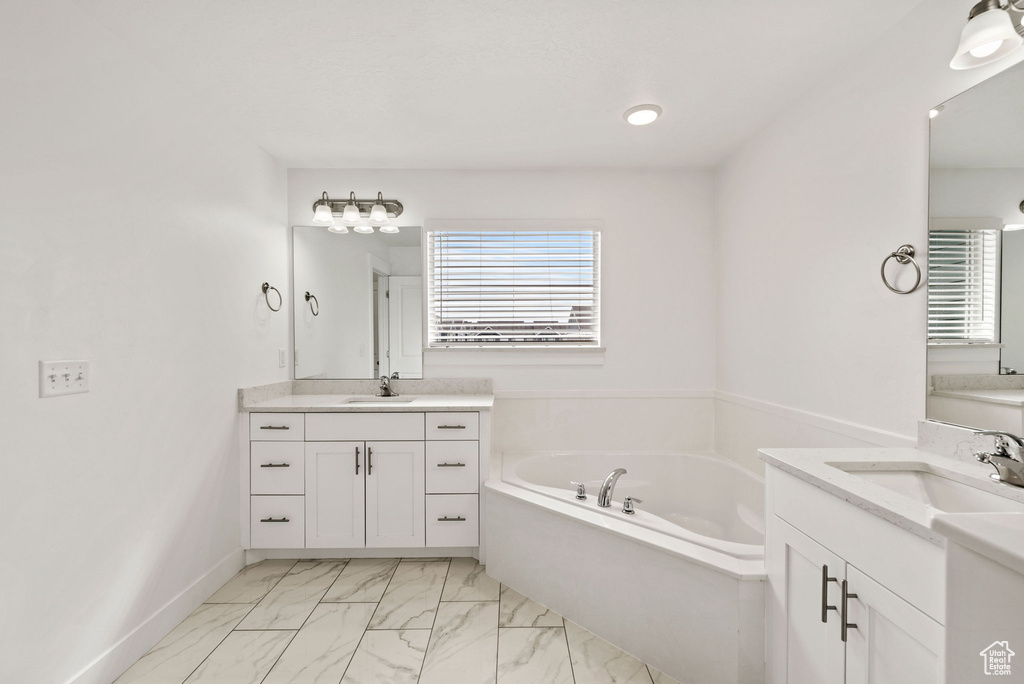 Bathroom with tile floors, dual sinks, large vanity, and a bath