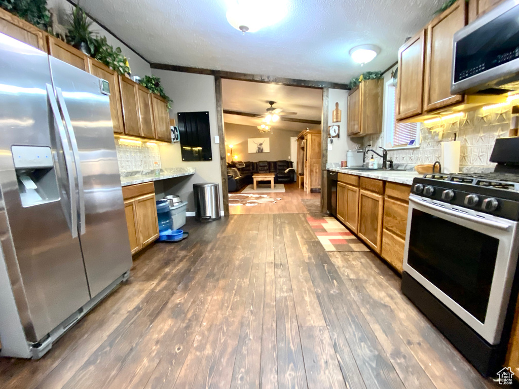 Kitchen with dark hardwood / wood-style flooring, stainless steel appliances, and tasteful backsplash