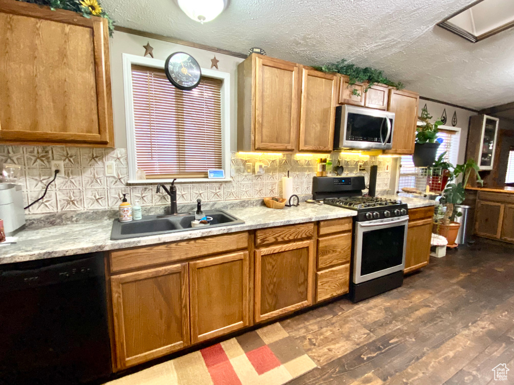 Kitchen featuring dark hardwood / wood-style flooring, appliances with stainless steel finishes, tasteful backsplash, and sink