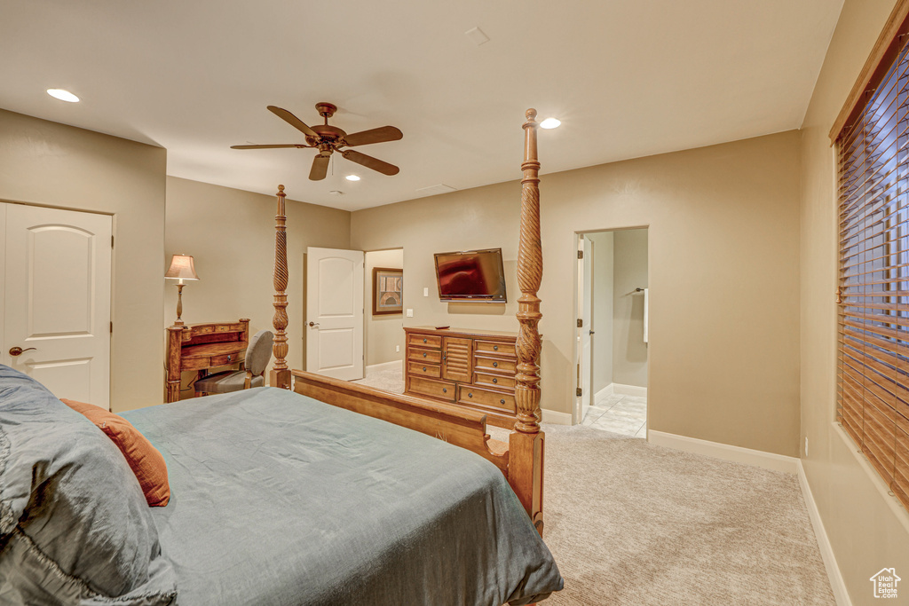 Bedroom with light carpet, connected bathroom, and ceiling fan