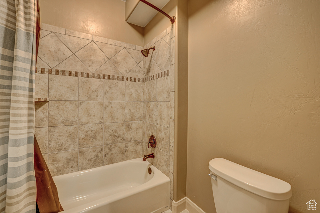 Bathroom featuring shower / bath combination with curtain and toilet